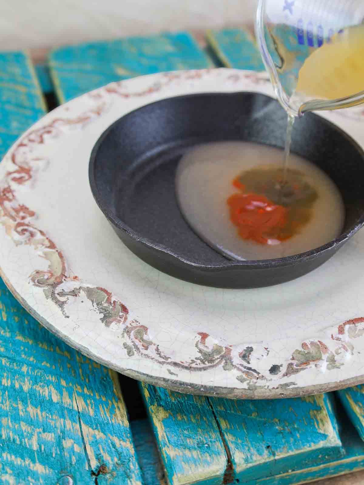 cast iron pan with vegetable broth and seasonings for refried beans.