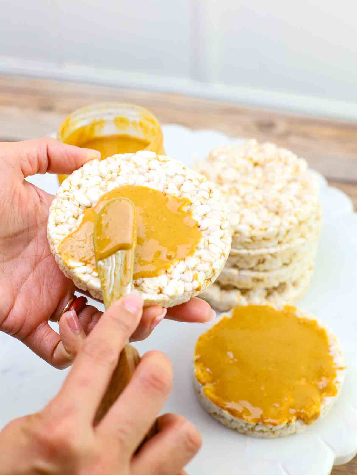 peanut butter being spread on rice cakes.