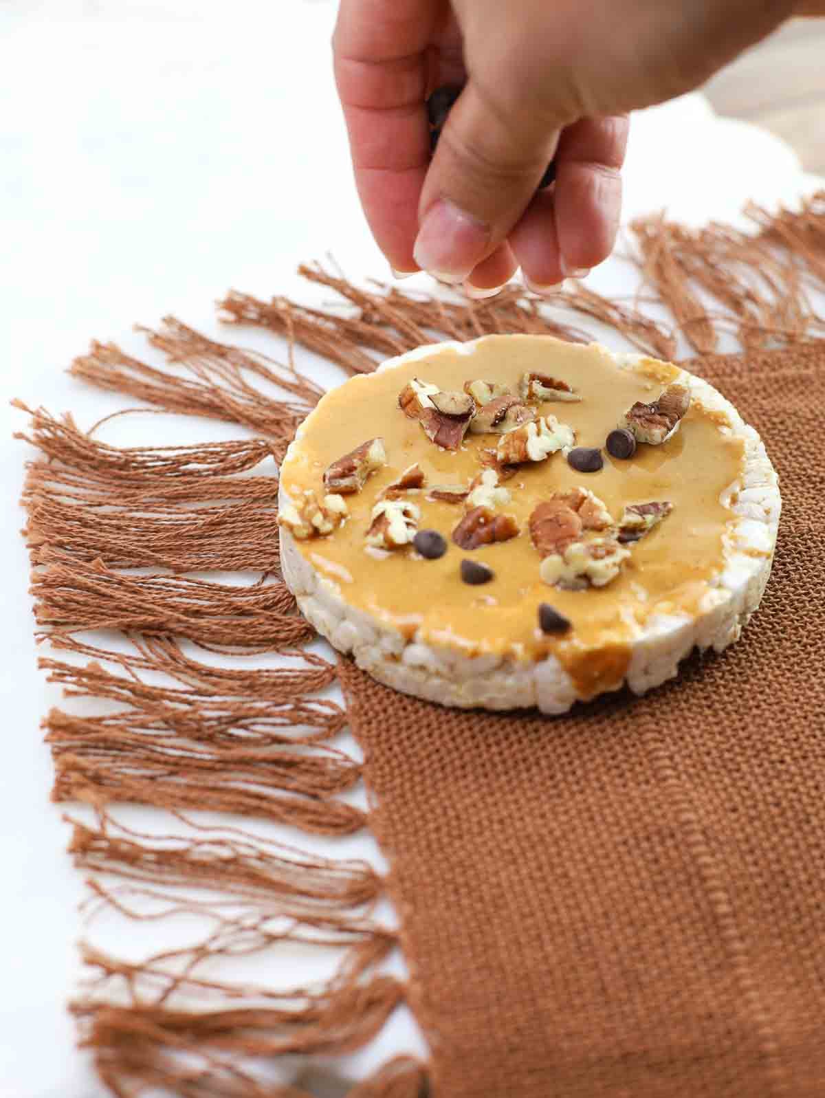 chocolate chips being sprinkled on a rice cake.