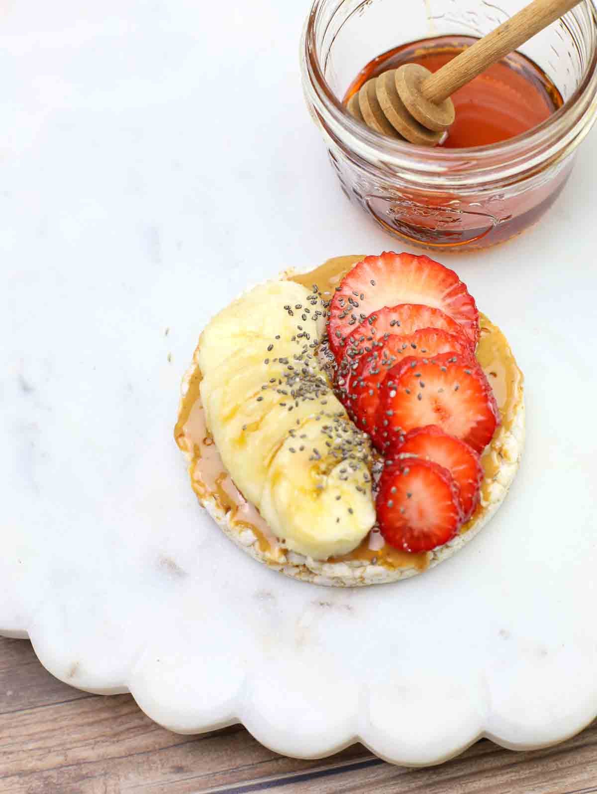 rice cake topped with peanut butter, banana slices, and strawberries.