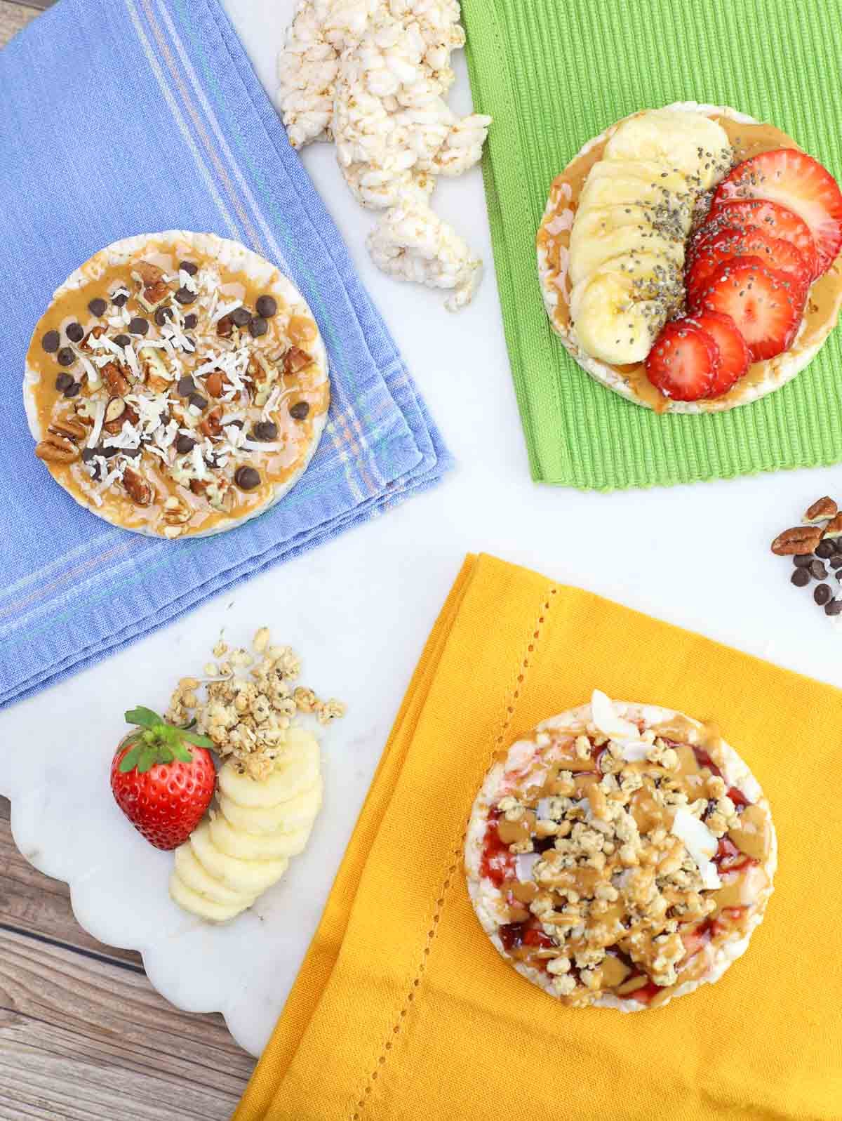 overhead shot of 3 rice cakes with different dessert toppings on colorful napkins.