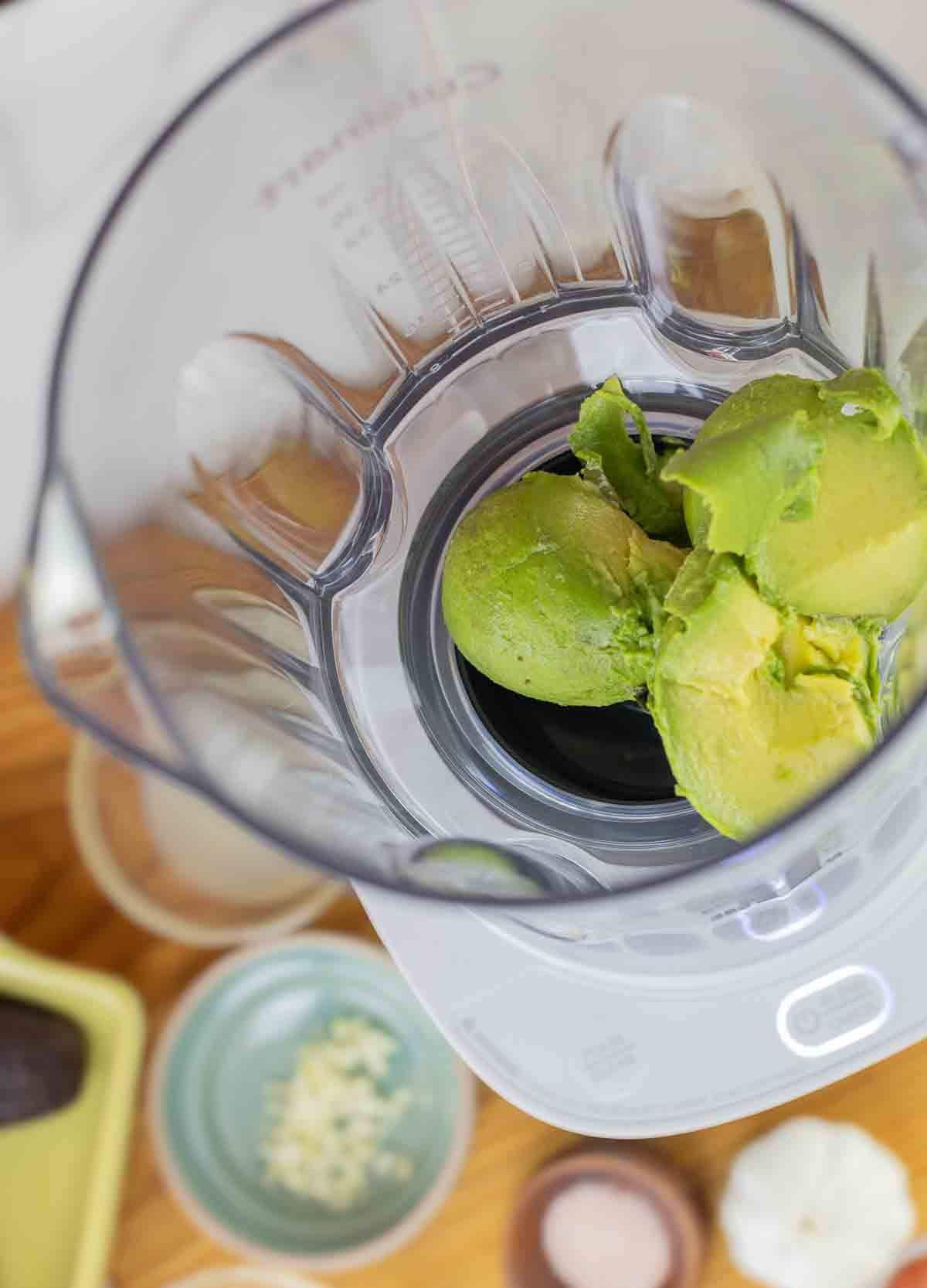 food processor with avocado and dressing ingredients before being blended. cropped