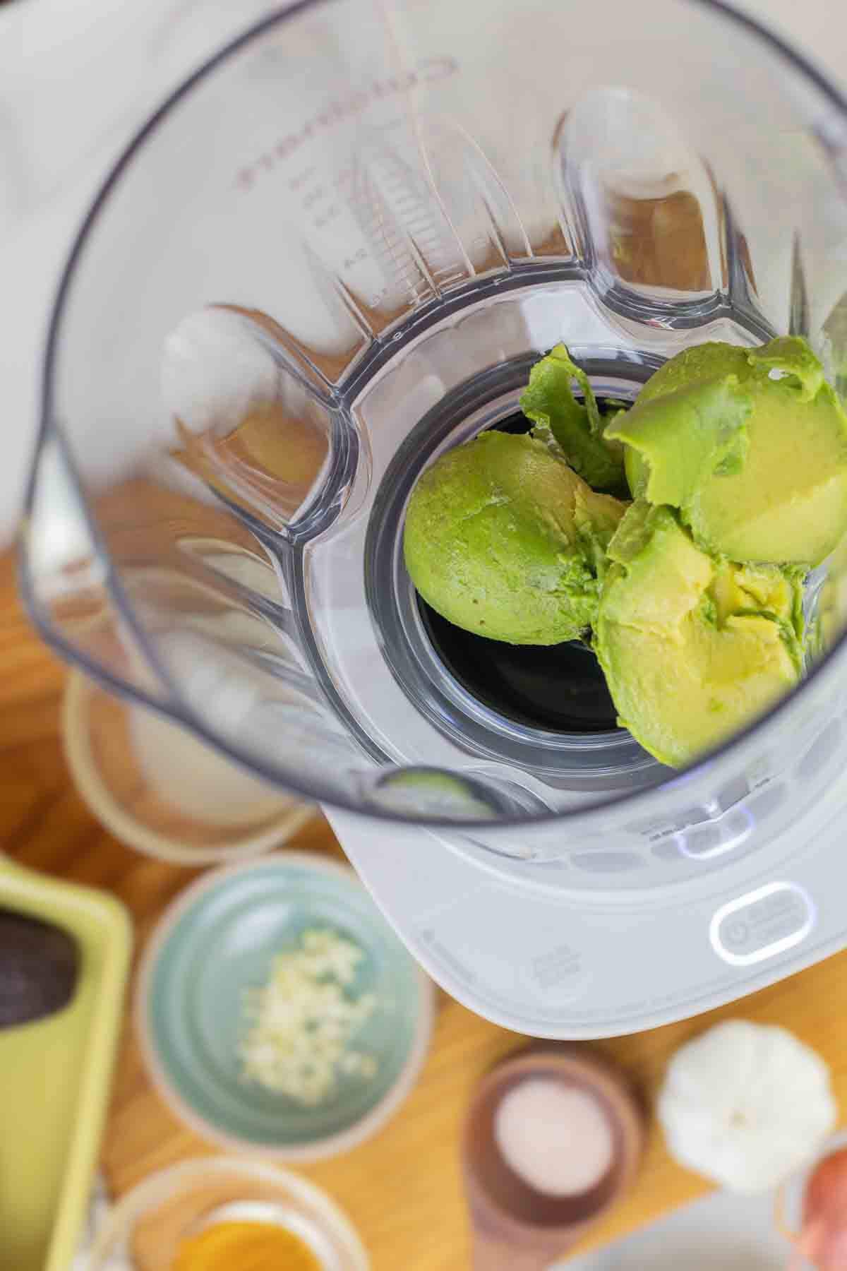 food processor with avocado and dressing ingredients before being blended.