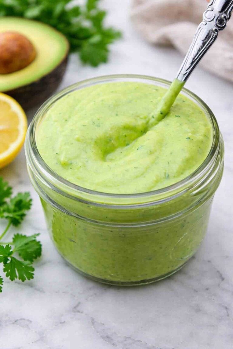avocado cilantro dressing in a small jar with a spoon.