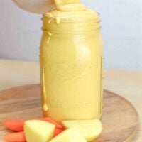 vegan cheese sauce in a mason jar with potato and carrot slices beside the jar.