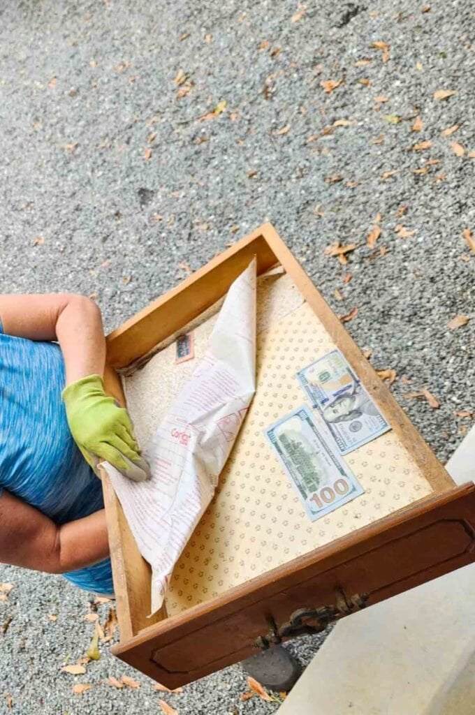 woman holding old empty drawer with money in it.