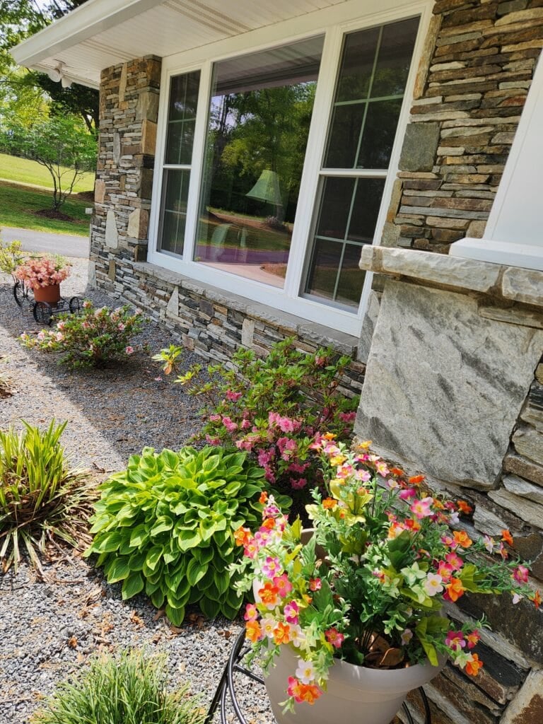 flowers blooming in flower bed and silk flowers in pots.