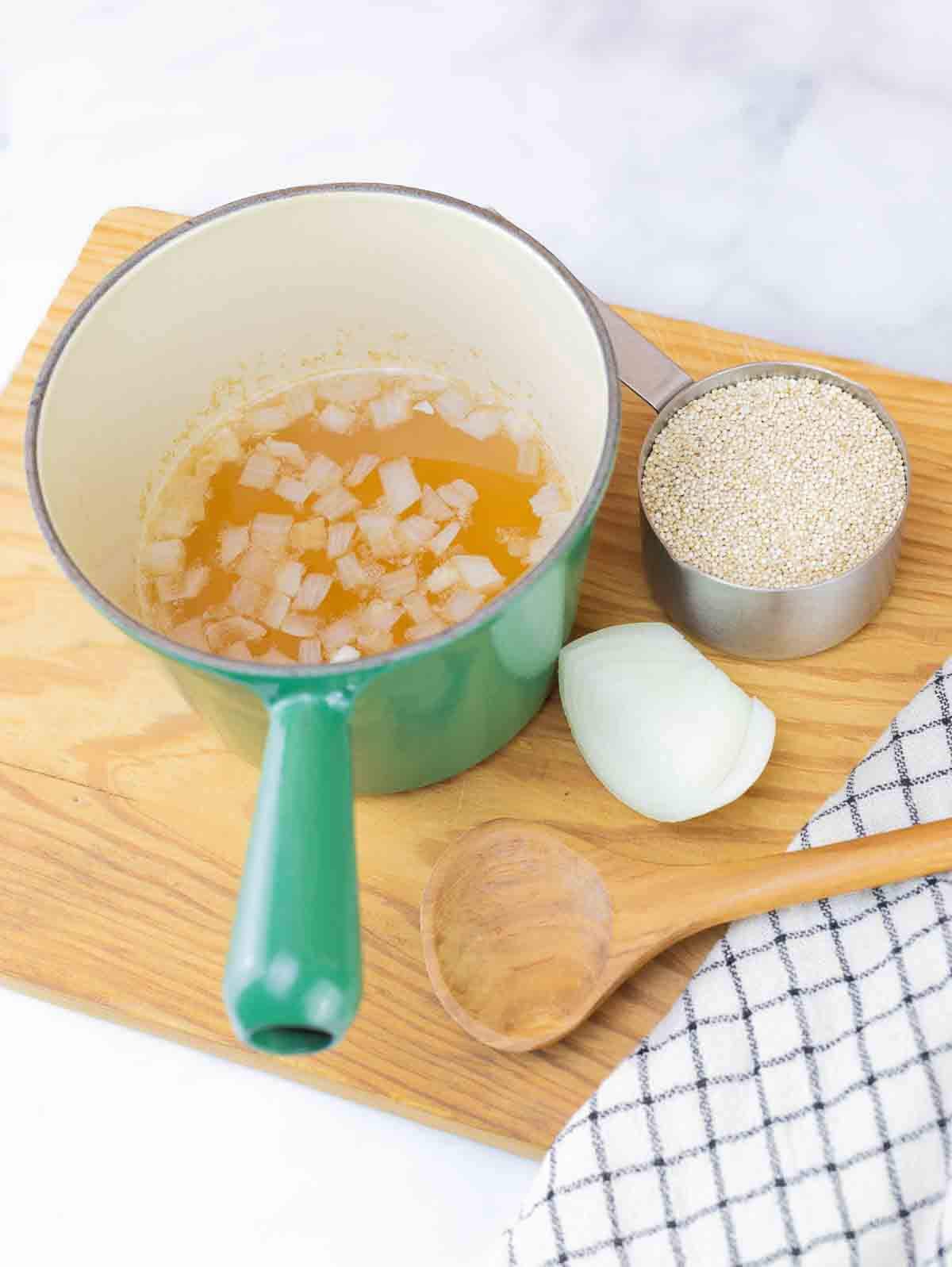 vegetable broth in saucepan for cooking quinoa. dry quinoa in measuring cup beside.