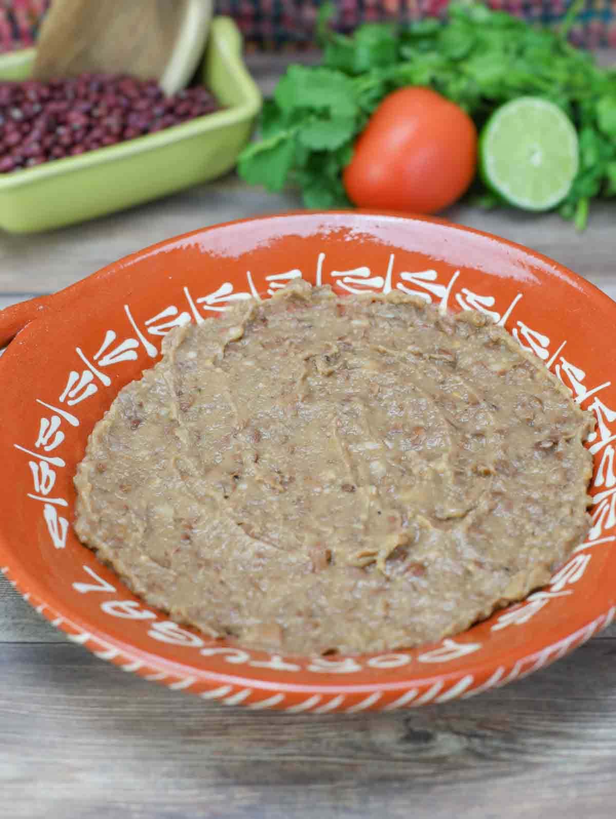 refried beans in bright orange bowl.