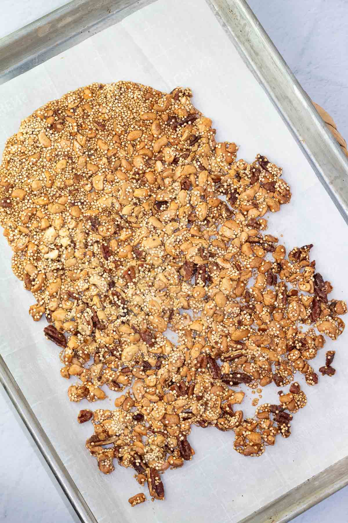 toasted nuts and quinoa on a baking sheet.