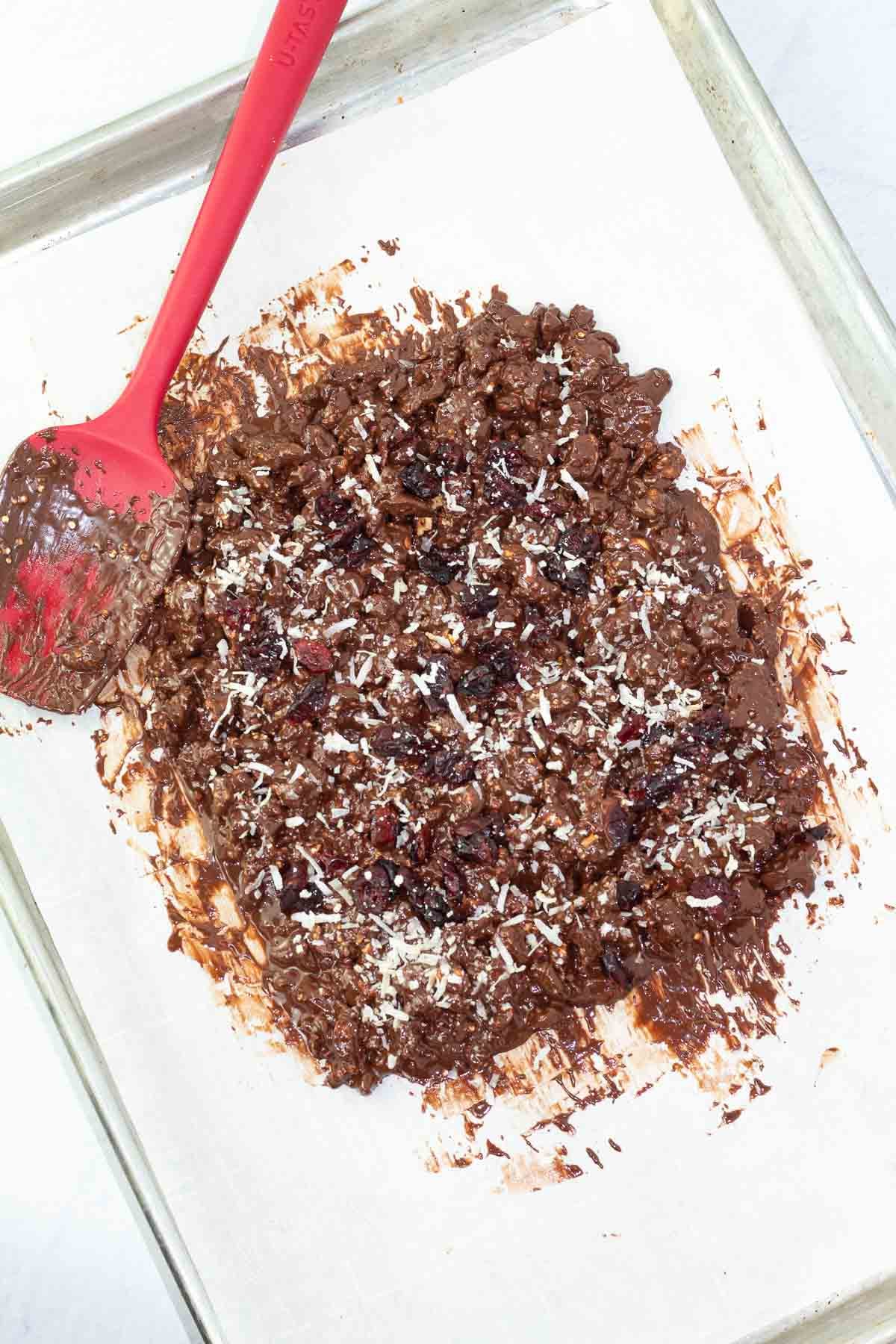 baking pan with mixture for chocolate bark on parchment paper spread out.