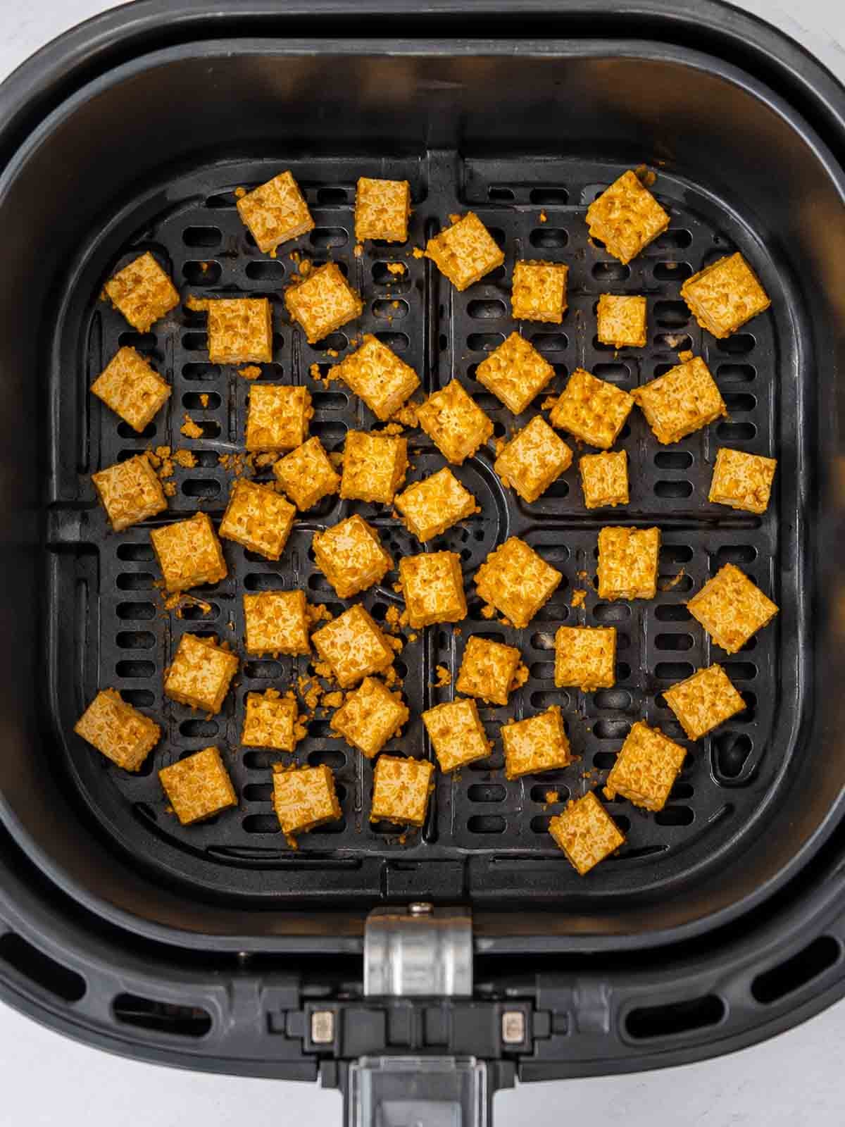 seasoned tofu in an air fryer basket.