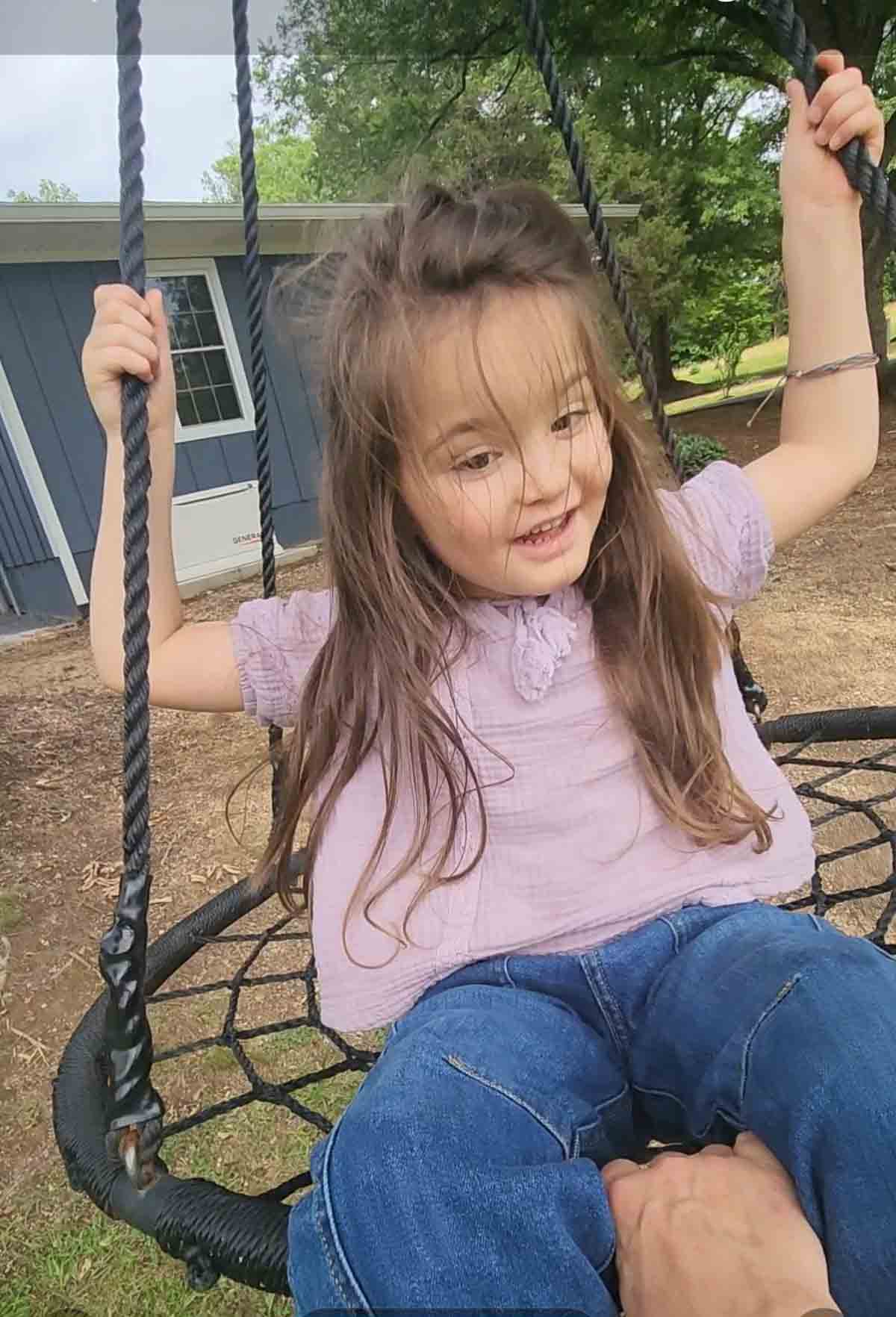 willow on a swing smiling and holding on.