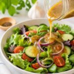 oil-free maple dijon dressing being poured over a garden salad.