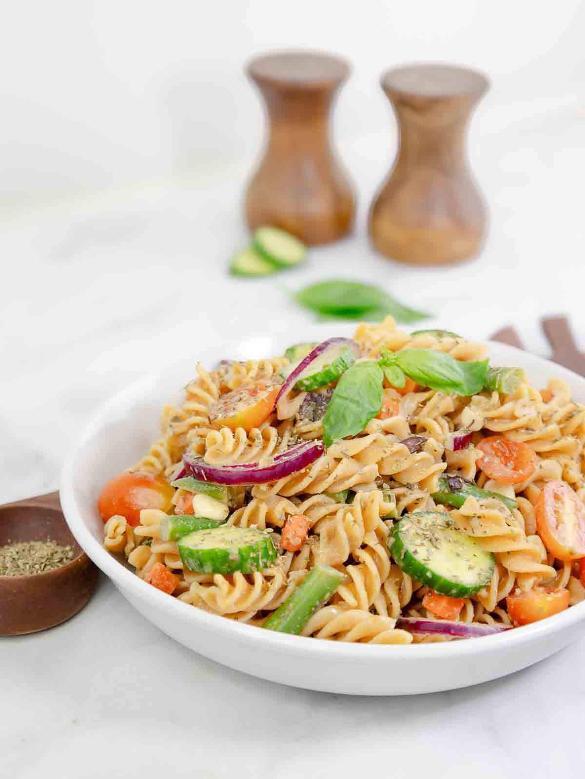 pasta salad with vegetables in bowl with seasonings.