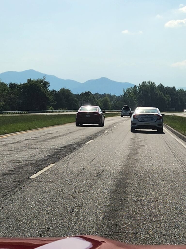 car on interstate driving towards mountains in the distance.