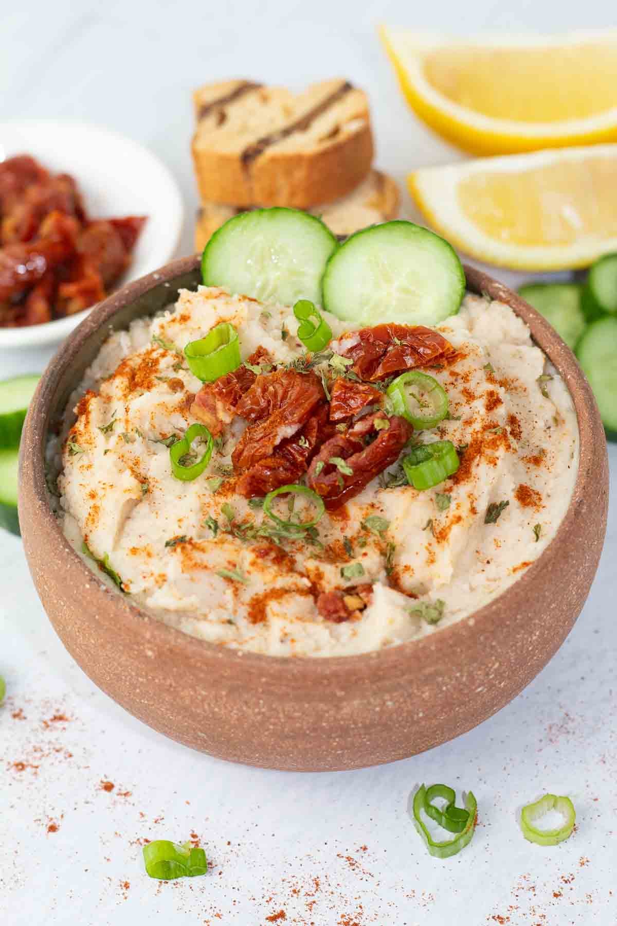 white bean dip in a handmade pottery bowl with cucumber slices.