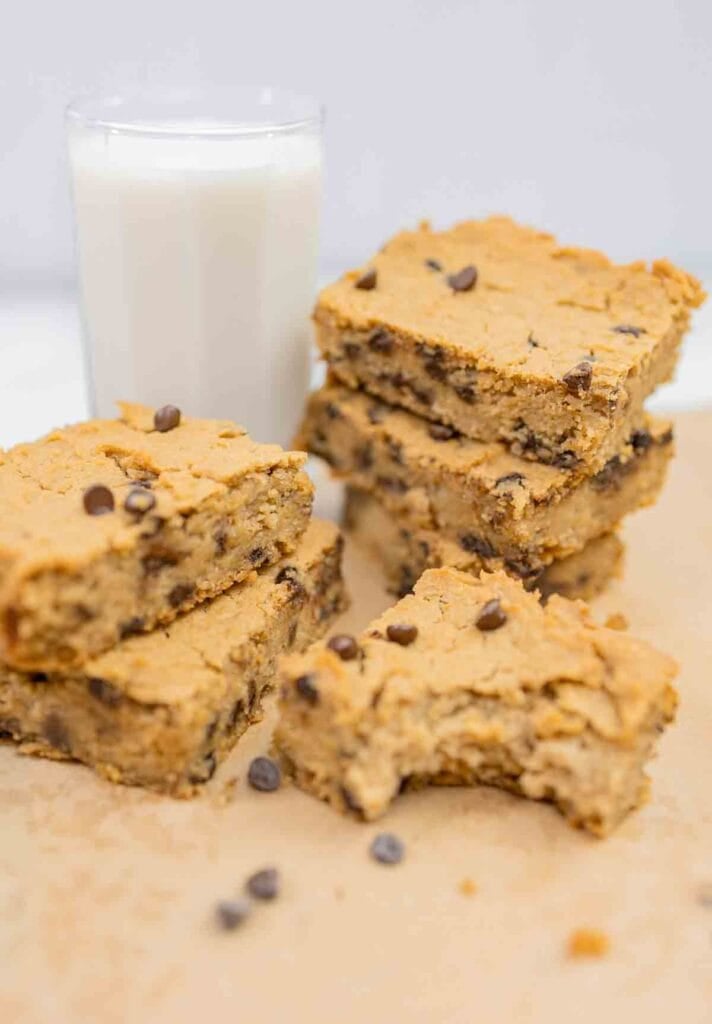 stacks of chickpea blondies with a glass of plant milk in background.