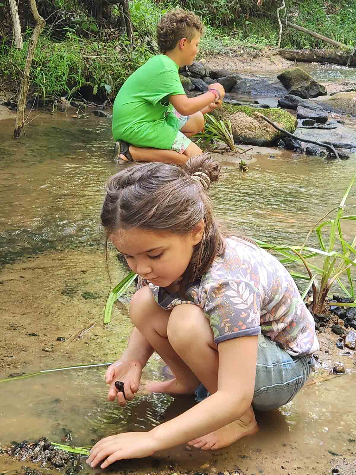 little girl and boy playing at the creek.