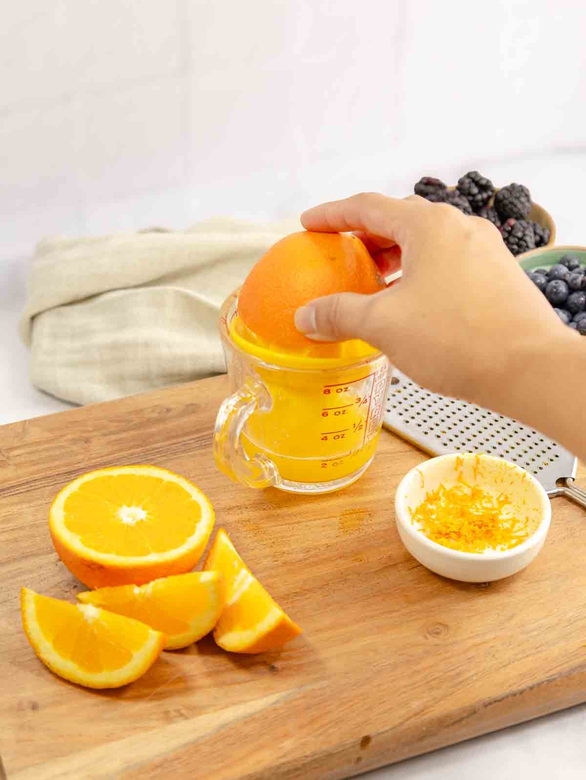 person juicing and orange in a measureing cup.