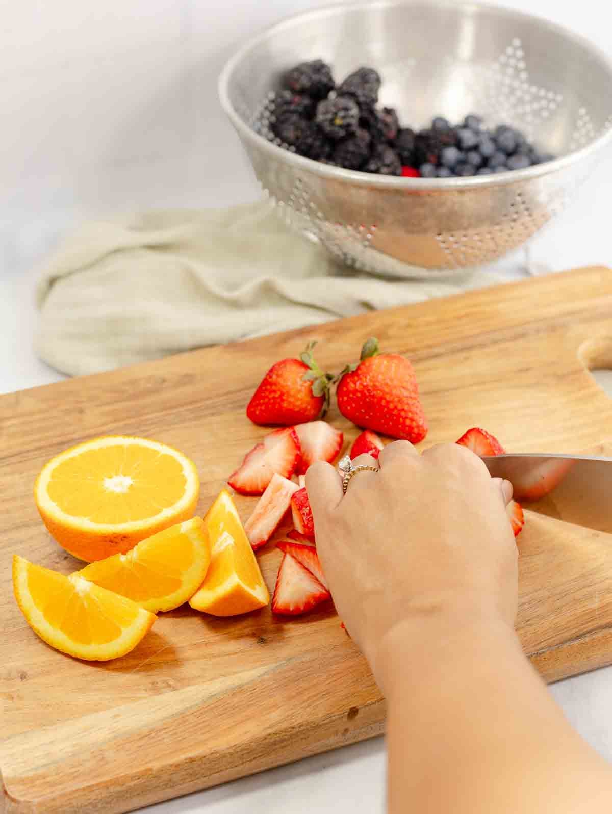 person slicing strawberries on a cutting board.