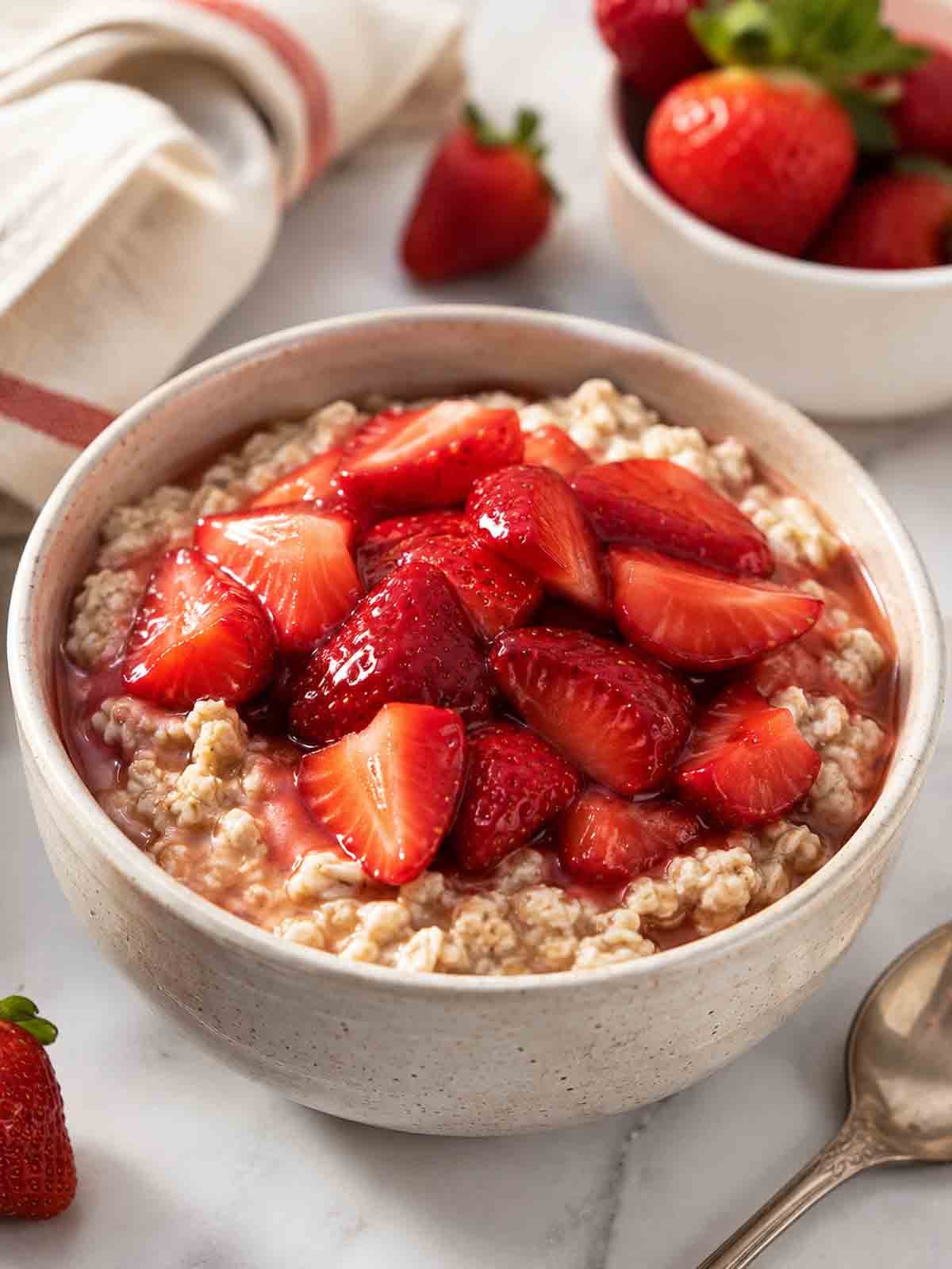 a bowl of oatmeal topped with macerated strawberries.