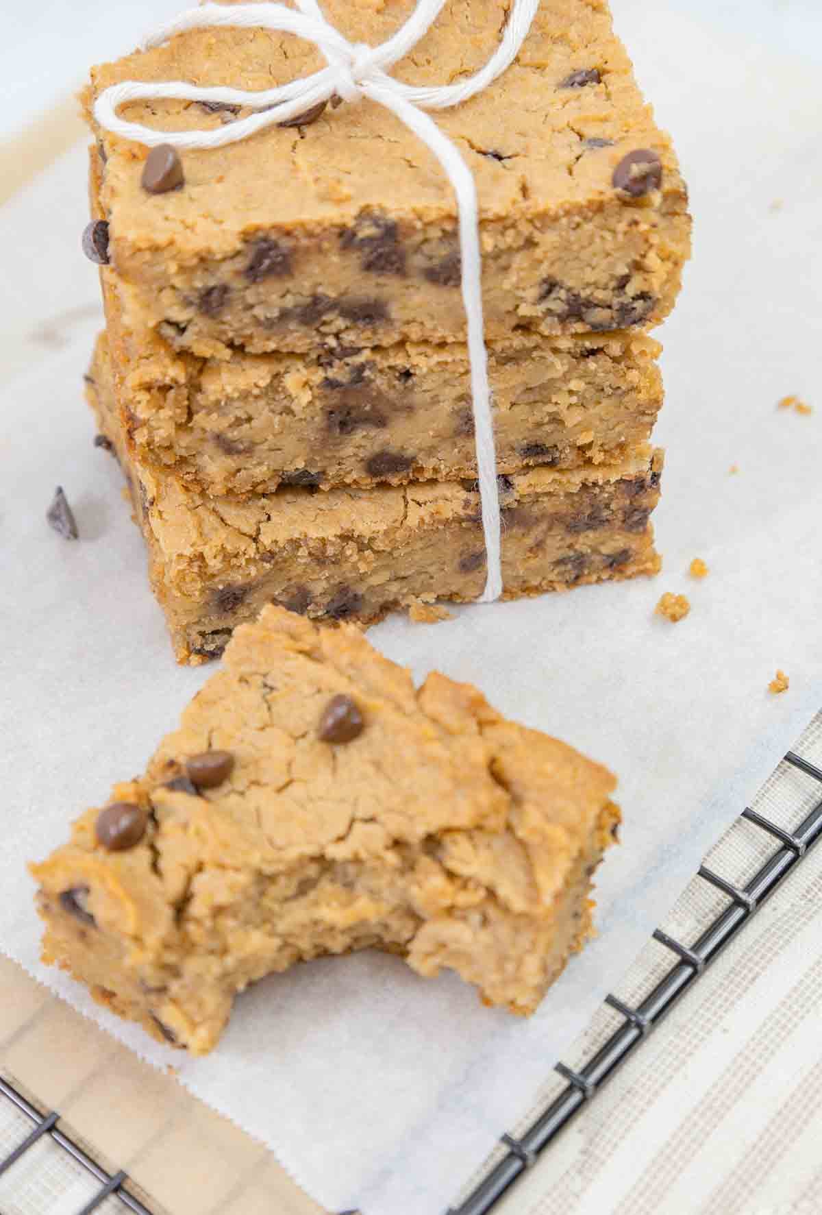 chickpea blondies stacked with one in front with bite out to show inside.