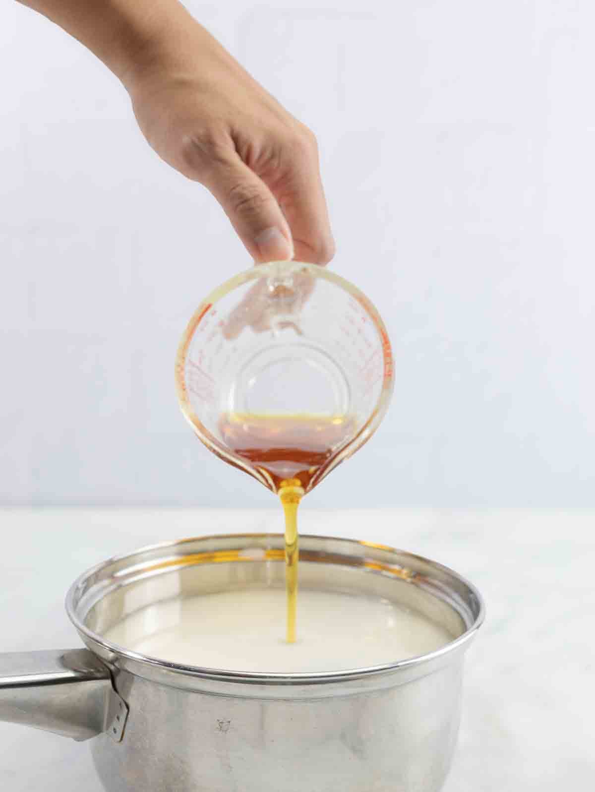maple syrup being poured into a pot of mexican rice pudding, in process shot.