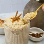 decorative glass with brown rice arroz con leche being served with a spoon.