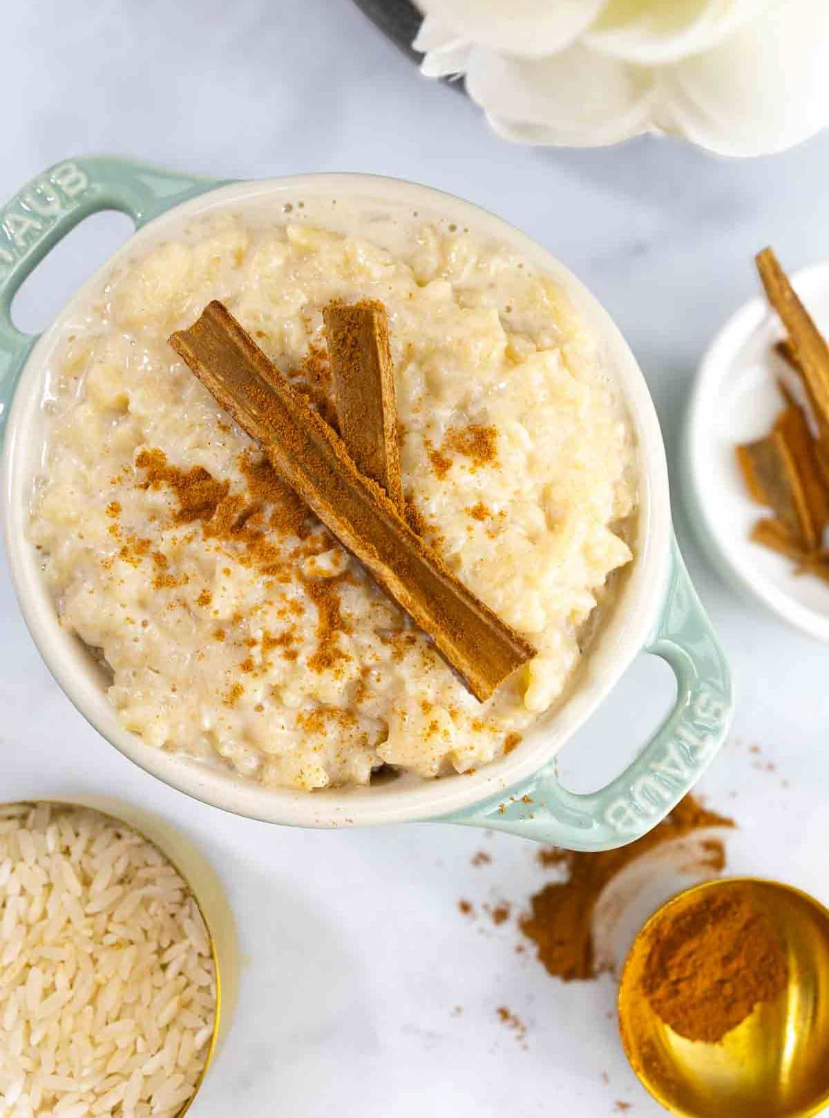 mexican rice pudding in a dish with handles and ingredients spread around it.