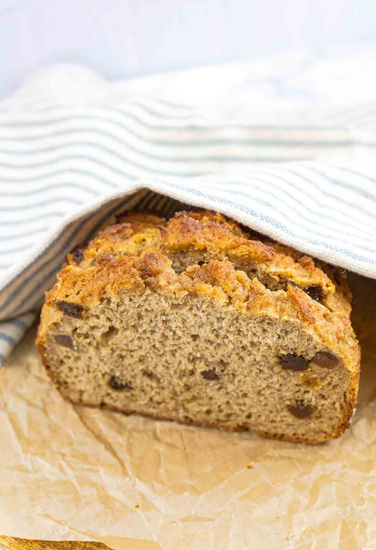 loaf of whole wheat cinnamon raisin bread under dish cloth.