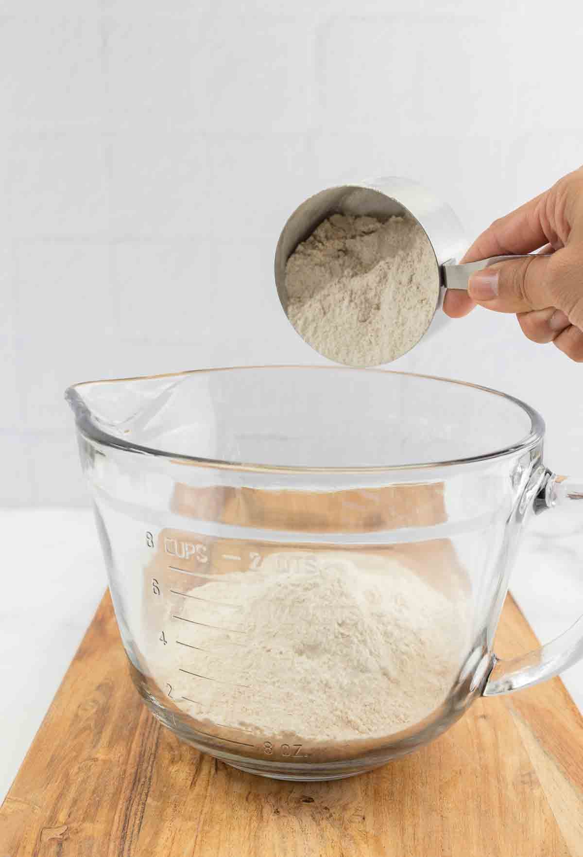 flour and other dry ingredients being poured into a mixing bowl.