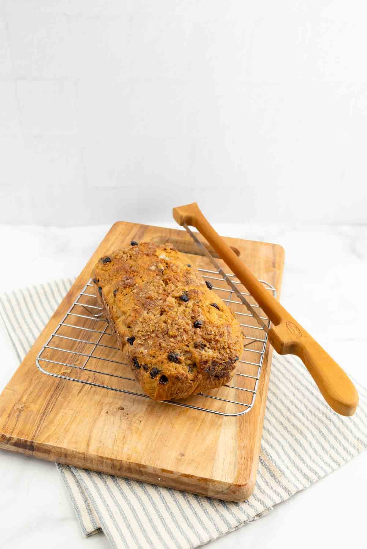 cinnamon bread with raisins on a cooling rack and cutting board.