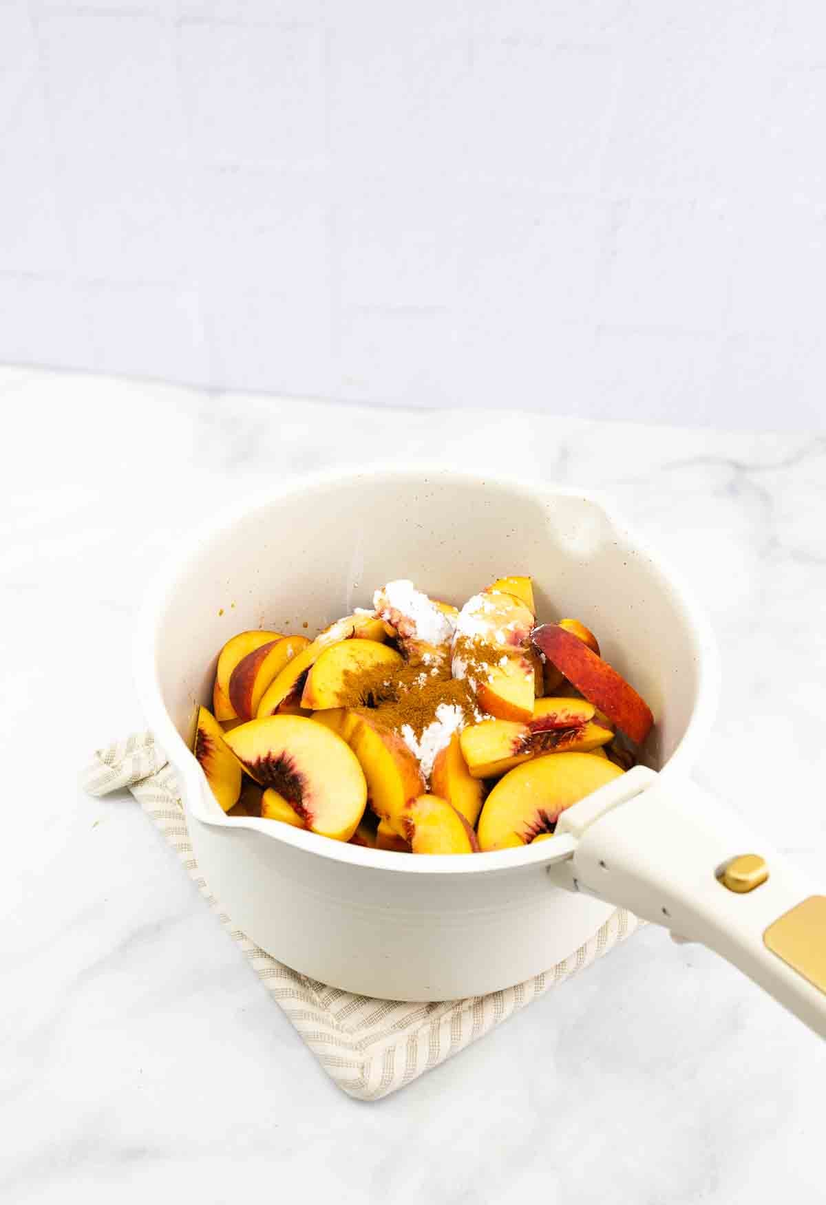 pot with fresh cut peaches and seasonings.
